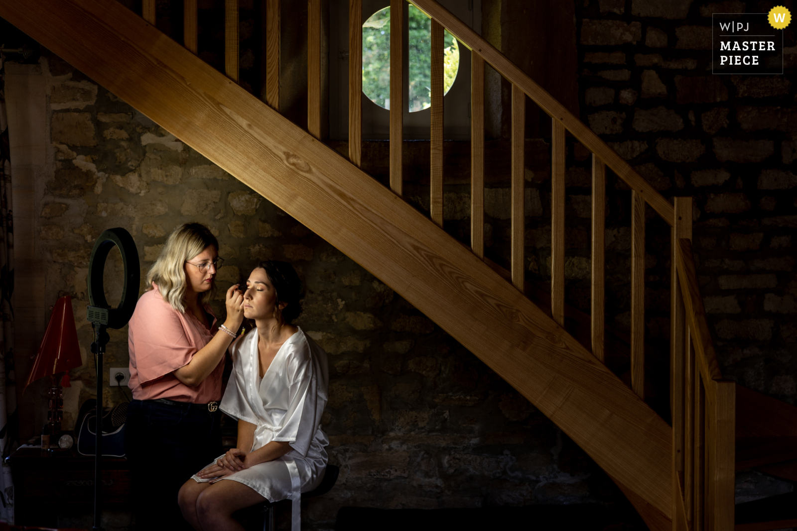 une mariée qui se fait maquiller sous un escalier